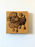A square canvas painting of a curly-haired poodle on a warm tan background, mounted on a plain white wall.