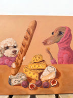Cheese & Company whimsical dog artwork showing two dogs surrounded by cheese, bread and picnic-style food