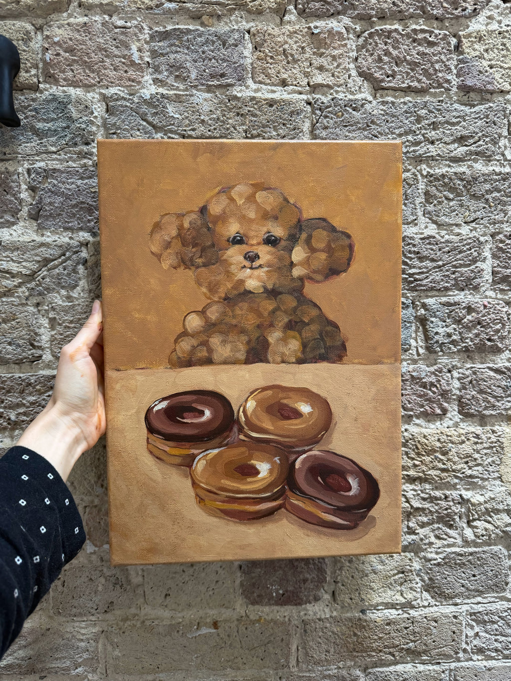 Eyes on Donuts whimsical dog and donuts artwork displayed against a textured brick wall